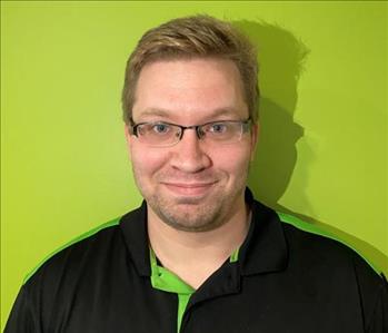 A white male wearing a SERVPRO polo against a green wall.