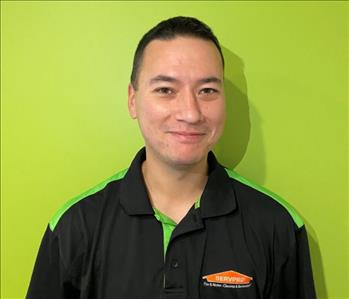A white male wearing a SERVPRO polo against a green wall.