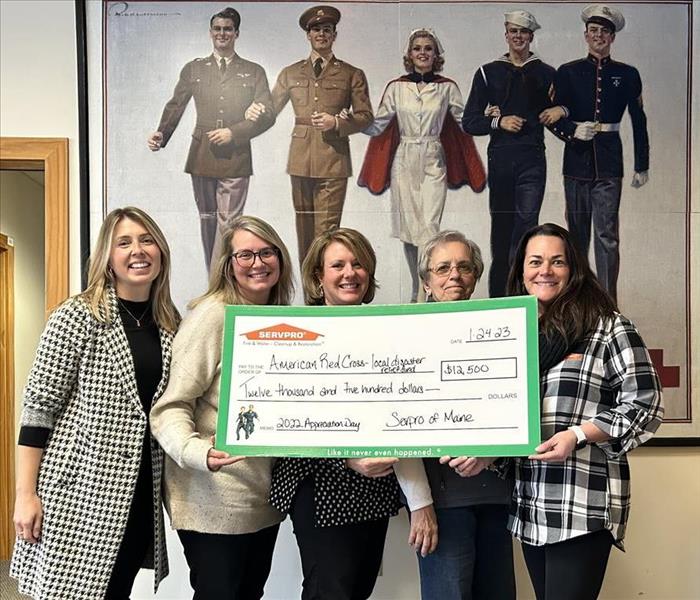 5 women standing in front of American Red Cross Picture holding a check